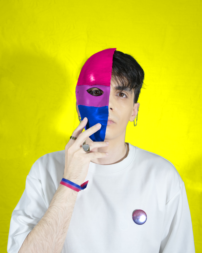 Alex Robles con media cara tapada con una máscara con la bandera de la bisexualidad.